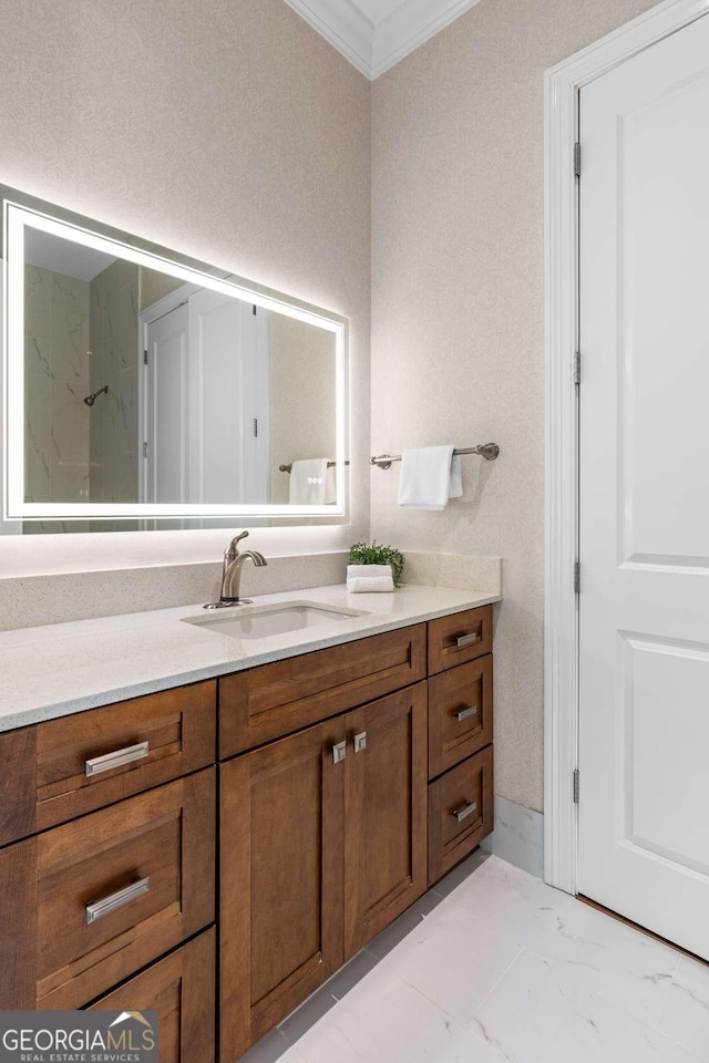 bathroom with marble finish floor, crown molding, and vanity