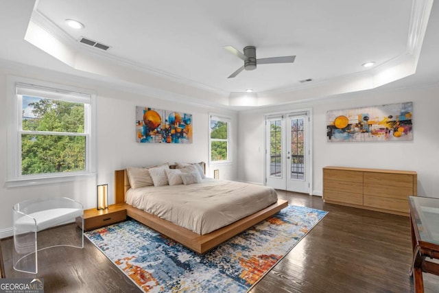 bedroom featuring dark wood-style floors, visible vents, a tray ceiling, and access to outside