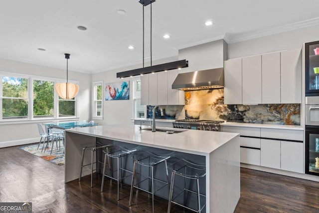 kitchen featuring wall chimney range hood, modern cabinets, light countertops, and a sink