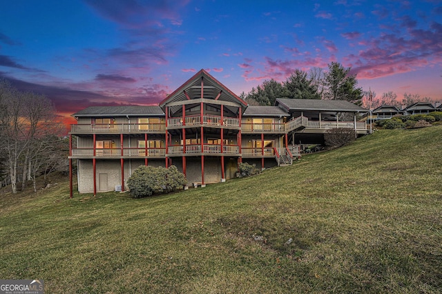 back of property at dusk with a deck and a yard