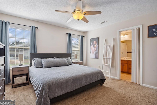 bedroom with multiple windows, a textured ceiling, and light colored carpet