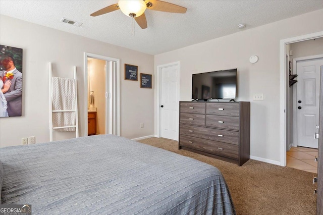 bedroom featuring baseboards, visible vents, a textured ceiling, and light colored carpet