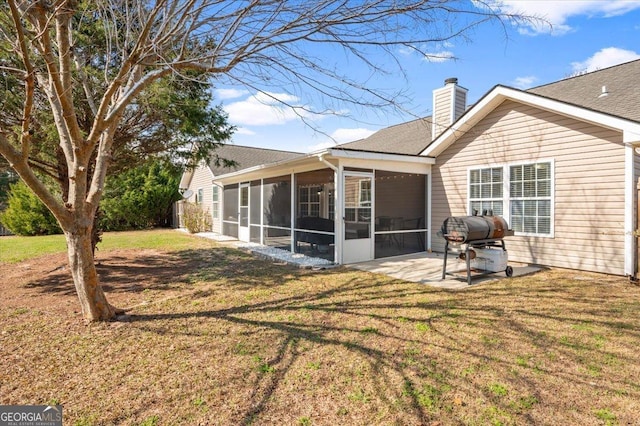 back of house featuring a lawn, a chimney, a patio area, and a sunroom