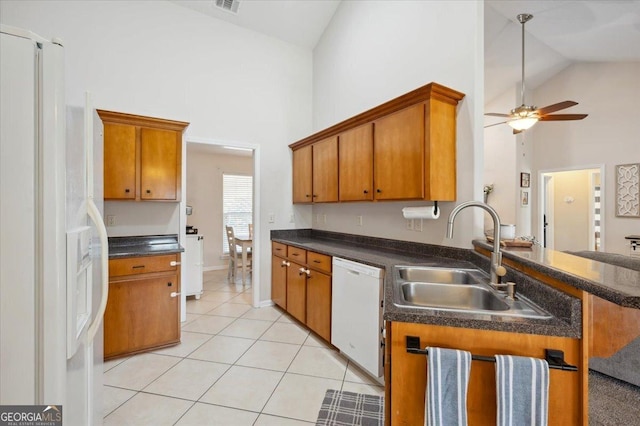 kitchen with dark countertops, white appliances, brown cabinets, and a sink