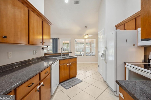 kitchen featuring white appliances, light tile patterned floors, visible vents, brown cabinetry, and a sink