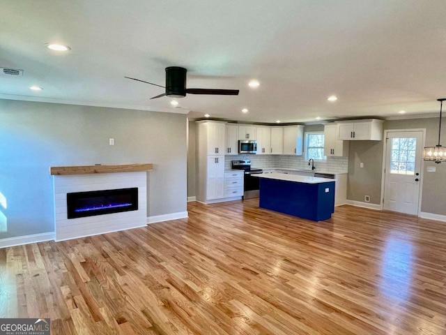 kitchen with white cabinetry, light countertops, hanging light fixtures, appliances with stainless steel finishes, and a center island