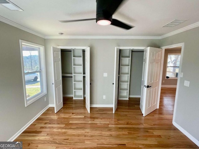 unfurnished bedroom featuring light wood-style floors, multiple windows, and ornamental molding