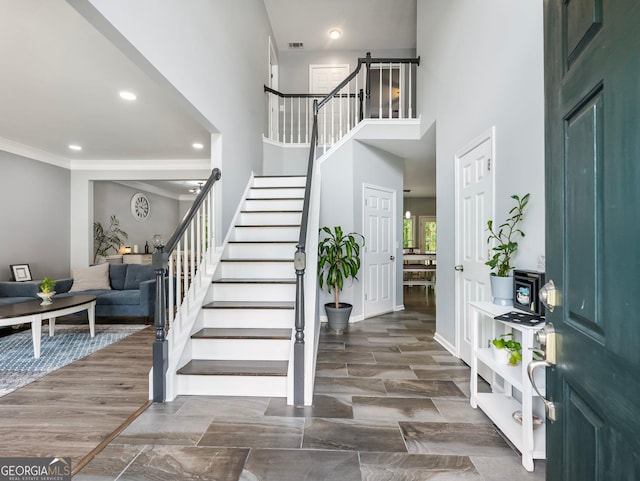 foyer entrance with visible vents, a high ceiling, stairs, crown molding, and recessed lighting