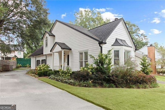 view of front of property with a shingled roof, concrete driveway, and a front yard