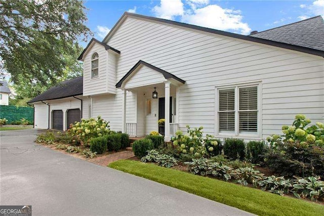 view of front of property featuring a garage, roof with shingles, and driveway