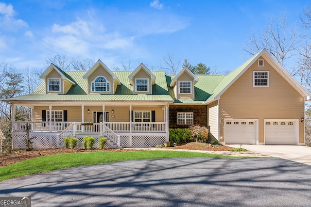 view of front of property featuring covered porch, an attached garage, concrete driveway, and metal roof