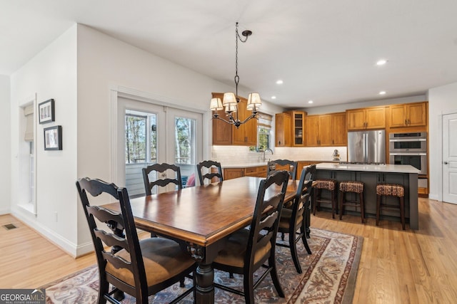 dining area with light wood finished floors, visible vents, baseboards, an inviting chandelier, and recessed lighting