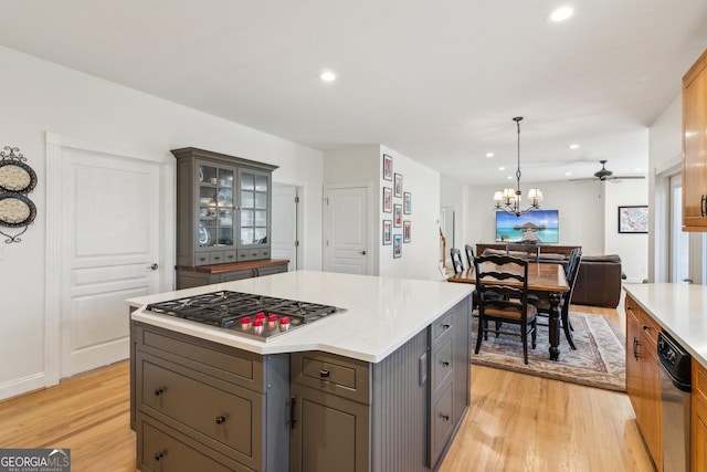 kitchen with open floor plan, stainless steel gas stovetop, gray cabinets, glass insert cabinets, and pendant lighting