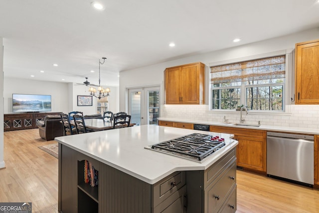 kitchen featuring a sink, light countertops, appliances with stainless steel finishes, a center island, and pendant lighting