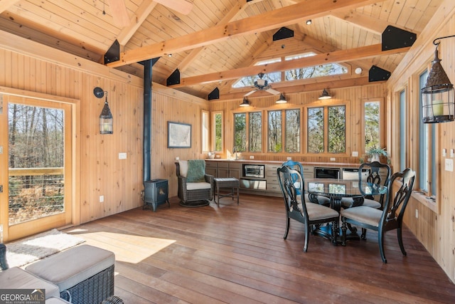 sunroom featuring wood ceiling, a wood stove, a healthy amount of sunlight, and lofted ceiling with beams