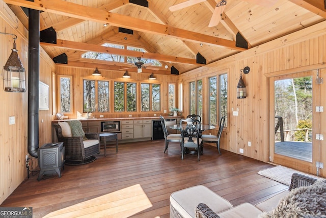 sunroom with vaulted ceiling with beams, wooden ceiling, a wood stove, and a ceiling fan