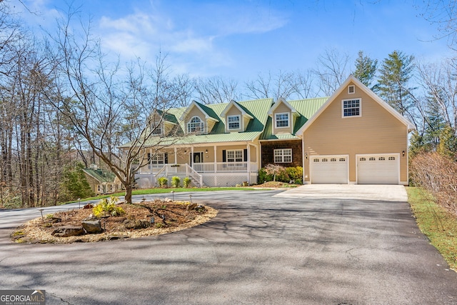 cape cod-style house with a porch, metal roof, and driveway