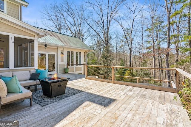 wooden terrace with an outdoor fire pit and a sunroom