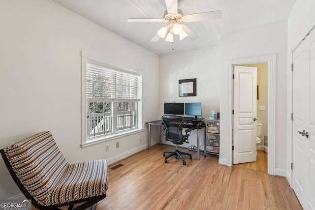 office space featuring light wood-style floors, visible vents, baseboards, and a ceiling fan