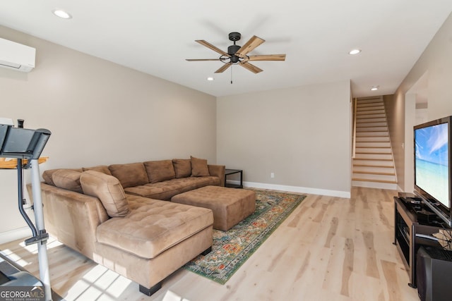 living area with light wood-type flooring, a wall unit AC, stairs, and baseboards