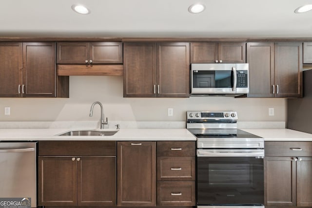 kitchen with light countertops, appliances with stainless steel finishes, a sink, and dark brown cabinets