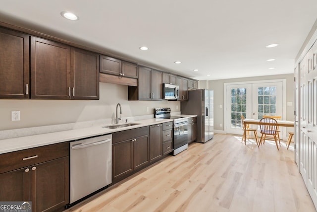 kitchen with dark brown cabinetry, stainless steel appliances, a sink, and light countertops