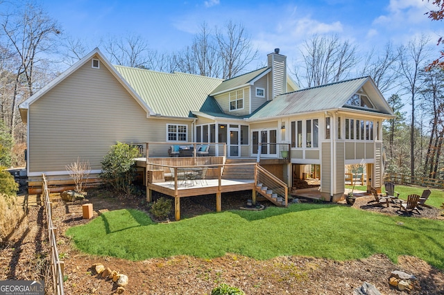 rear view of property featuring a deck, metal roof, a sunroom, stairs, and a chimney