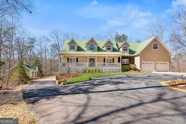 cape cod-style house featuring a garage, metal roof, aphalt driveway, and a porch