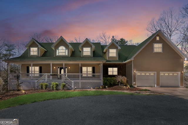 view of front of home with a garage, covered porch, metal roof, and concrete driveway