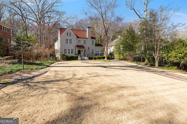 exterior space with a tiled roof, a chimney, and stucco siding