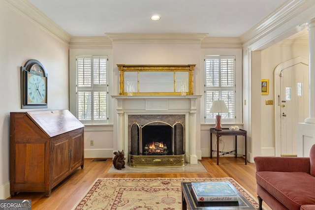 sitting room with a fireplace, crown molding, light wood-style flooring, and baseboards