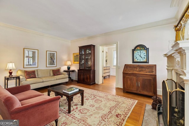 living area featuring ornamental molding, light wood-type flooring, a fireplace with flush hearth, and baseboards