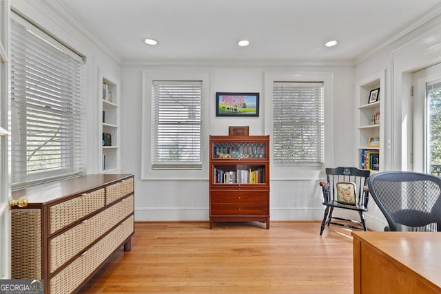 living area featuring plenty of natural light, built in shelves, and ornamental molding