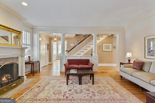 living area with light wood-style flooring, stairway, crown molding, and a high end fireplace