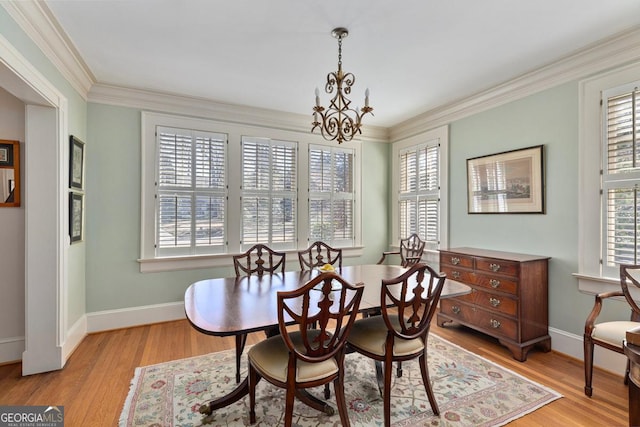 dining area with a notable chandelier, light wood finished floors, baseboards, and crown molding