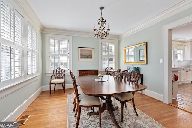 dining room with light wood-type flooring, visible vents, and crown molding