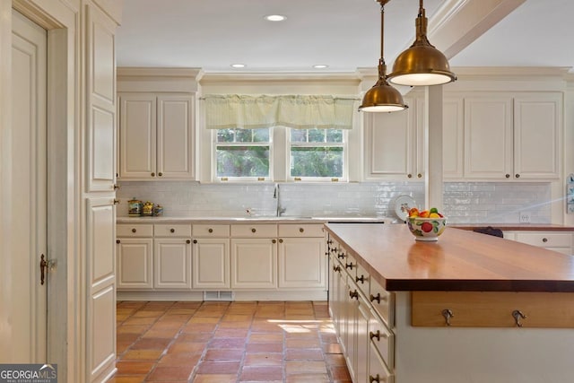 kitchen with visible vents, a kitchen island, hanging light fixtures, wooden counters, and a sink