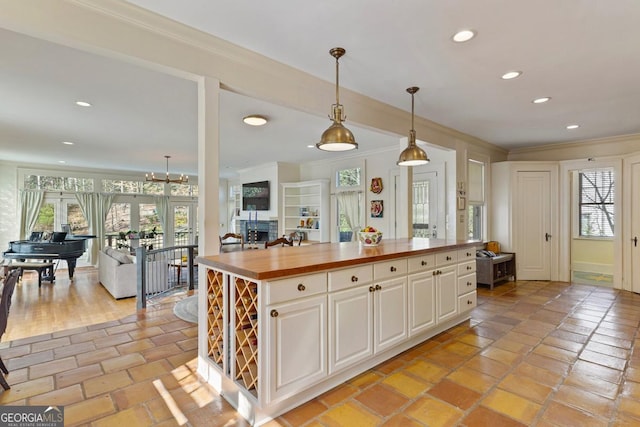 kitchen featuring open floor plan, butcher block countertops, a kitchen island, and decorative light fixtures