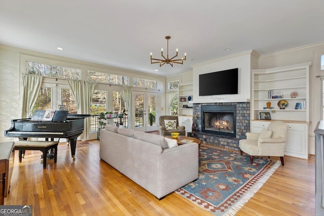 living room featuring a healthy amount of sunlight, light wood-style floors, a lit fireplace, and french doors