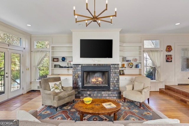 living area with a tile fireplace, built in features, french doors, and ornamental molding