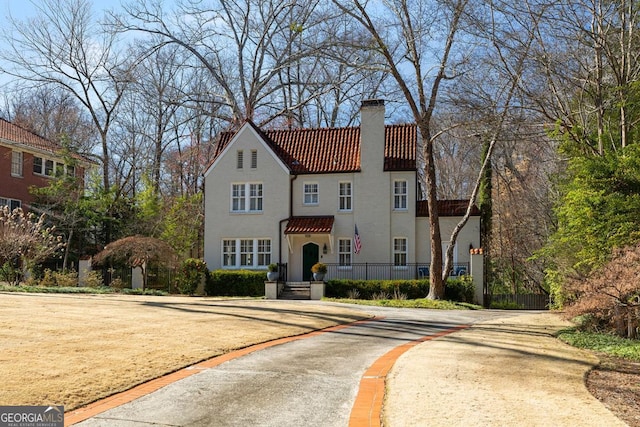 mediterranean / spanish home featuring stucco siding, a chimney, and a tiled roof