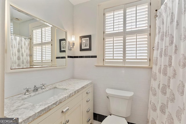 full bathroom featuring curtained shower, toilet, a wainscoted wall, vanity, and tile walls