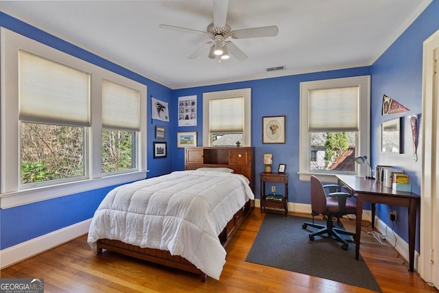 bedroom with baseboards, visible vents, ceiling fan, and wood finished floors