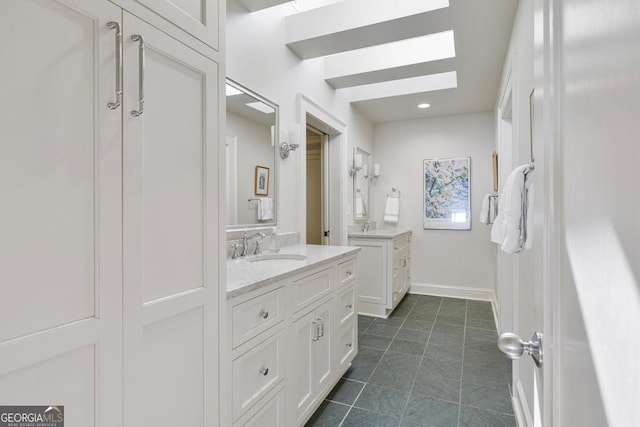 bathroom featuring a sink, baseboards, two vanities, and tile patterned floors