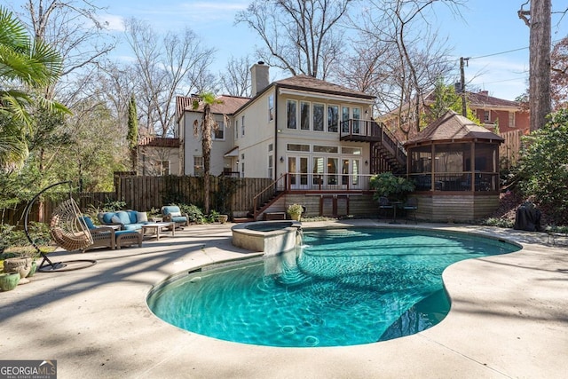 view of swimming pool with a pool with connected hot tub, a sunroom, a patio area, fence, and stairs