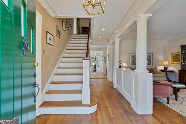 entrance foyer with crown molding, decorative columns, recessed lighting, stairway, and light wood-style flooring