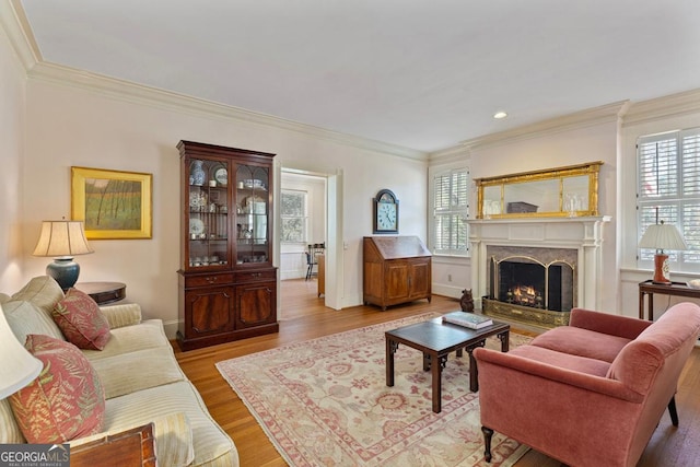 living room featuring light wood-style floors, baseboards, a premium fireplace, and ornamental molding