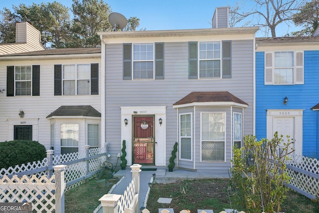 townhome / multi-family property featuring fence and a chimney