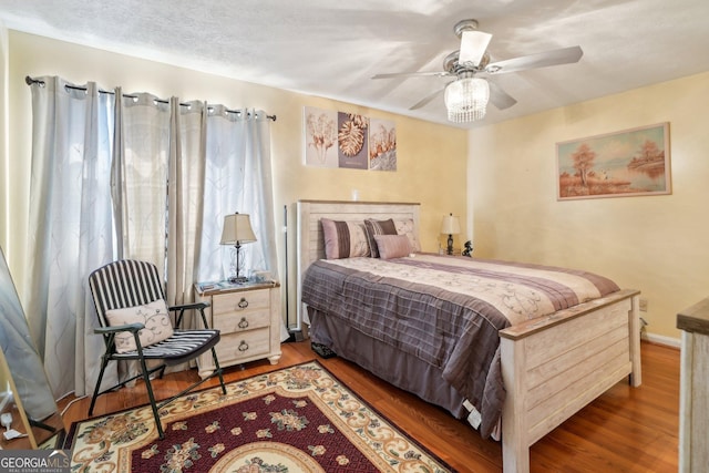 bedroom with a textured ceiling, baseboards, and wood finished floors