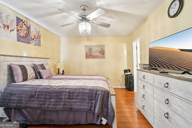 bedroom with light wood-type flooring, ceiling fan, and baseboards